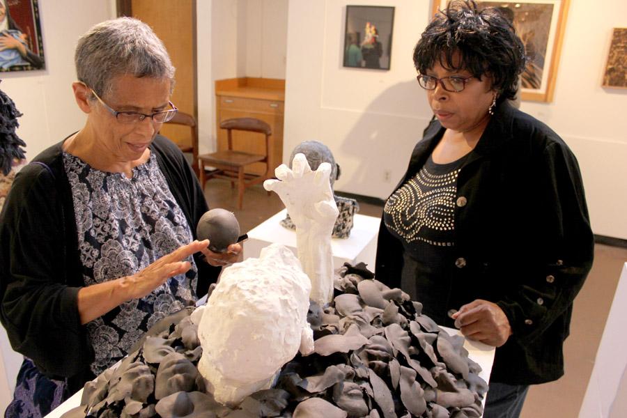 Oakland resident Lorraine Bonner (left) describes her piece titled Devourer to Brentwood resident Julee Richardson (right) during the art reception in the Eddie Rhodes Gallery on Friday.
