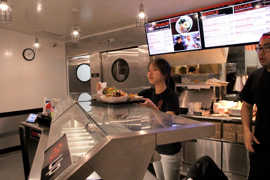 Two employees at Koja Kitchen in Berkeley serve up dishes on Sept. 17.