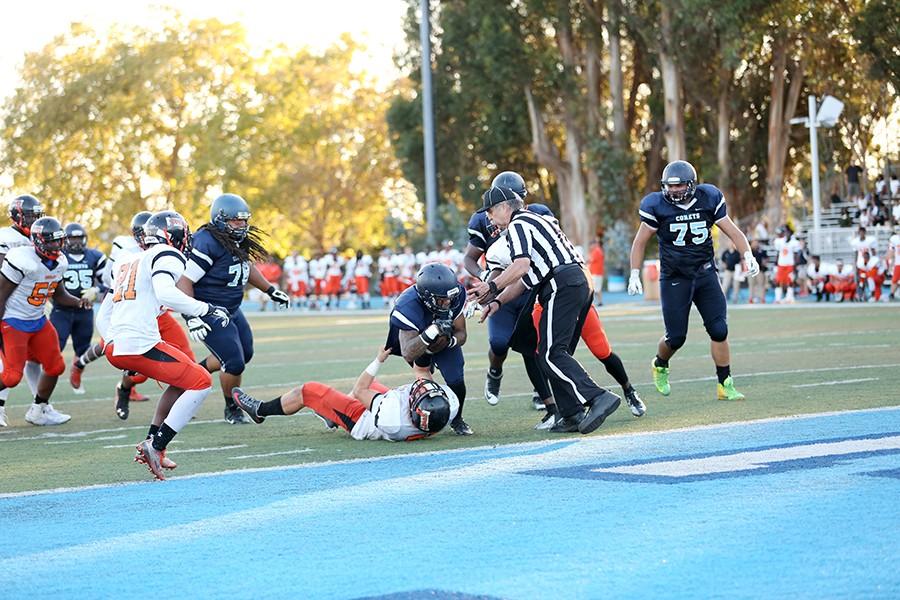 Comet running back Robert Wilkes plows over Tiger linebacker Clay Jones and into the end zone during Contra Costa College’s 37-28 win against Reedley College on Saturday at Comet Stadium. 