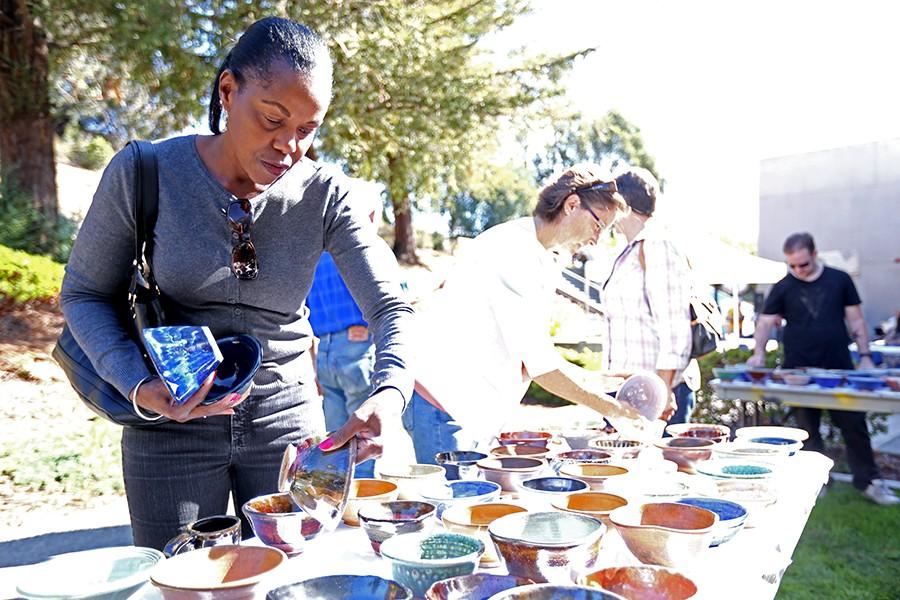 Local resident Denise Maloney examines a bowl during the Empty Bowls project event at the Applied Arts Building Patio outside of the Three Seasons Restaurant on Friday.