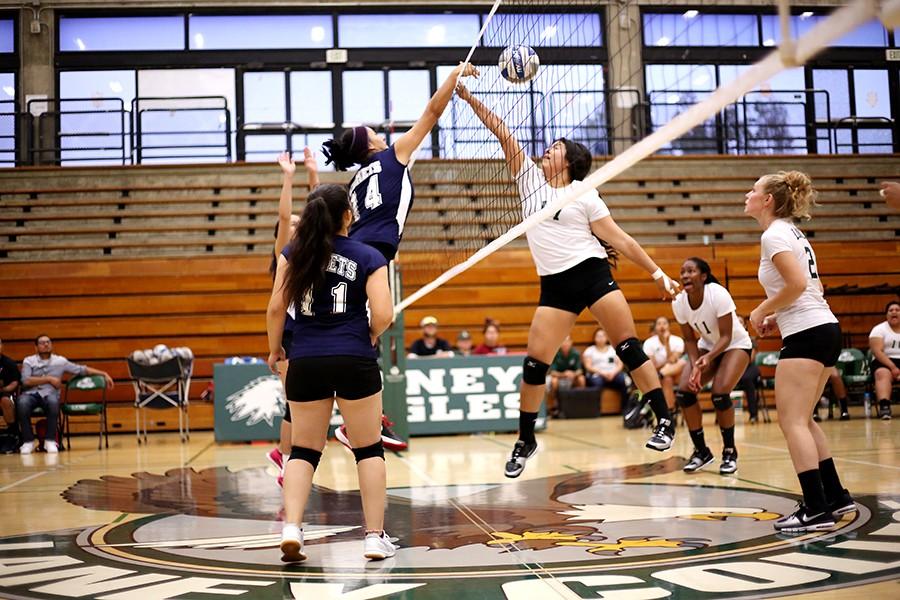 Comet right hitter Amy Palomares tips the ball over the net and Eagle middle blocker Stephanie Sandria during Contra Costa College’s loss to Laney College in Oakland on Friday.  