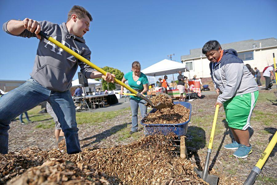 Kinesiology Major Andrew Lilly (left), health and human services major Shelby Wichner and Pinole resident Allen Pablo shovel gravel into wheelbarrows to spread across the lot to deter weed growth and beatify the area during the Youth Service Day on the Richmond Greenway event at South 42 St & Ohio Ave on Saturday.