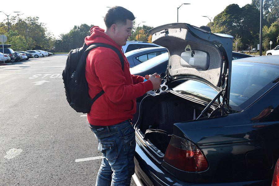Business major JayJay Douangpinya pulls out a beverage from his trunk before heading to class in Contra Costa College’s Parking Lot 3  on Monday. 