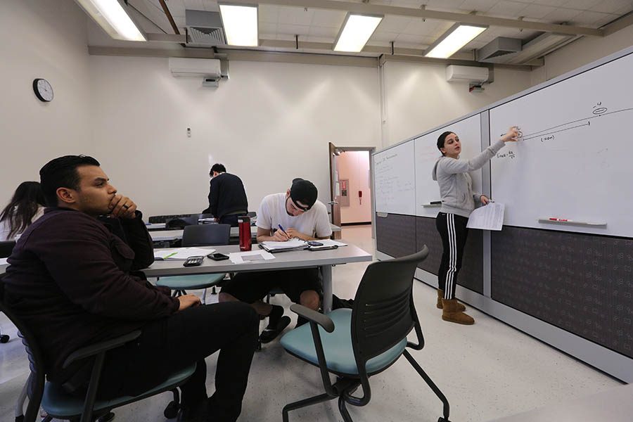 Biology major Oscar Castillo (left) listens to biology major Maria Rodriguez (right) explain a problem using the new whiteboard and equipment in PS-109 in the Physical Science Building on Monday.
