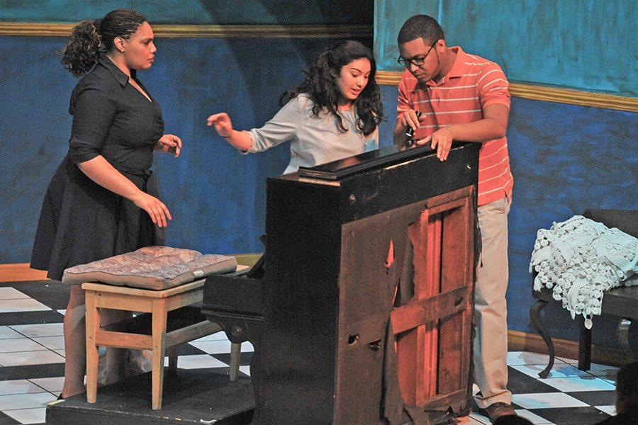 Piano tuner Victor Manuel (right) played by Sean Teal, flashes a light into a piano as Sofia Celia, played by Jelaine Maestas, and Maria Celia, played by Akilah Kamau, watch during a performance of “Two Sisters and a Piano” in the Knox Center on Thursday.Piano tuner Victor Manuel (right) played by Sean Teal, flashes a light into a piano as Sofia Celia, played by Jelaine Maestas, and Maria Celia, played by Akilah Kamau, watch during a performance of “Two Sisters and a Piano” in the Knox Center on Thursday.