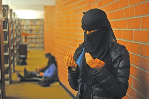 Muslim student prays
in the behind the book- shelves in the Library on March 20. The Muslim Student Association is coordinating efforts
to create a designated space for praying.