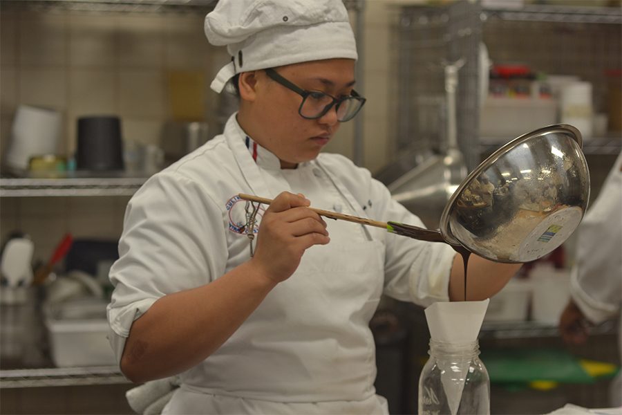 Culinary arts major Carissa Garcia pours a chocolate mix into a cone the Aqua Terra Grill kitchen area on Tuesday.
