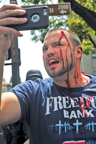 A pro-Trump supporter records himself bleeds after clashing with anti-Trump protesters during Patriots Day pro-Trump rally in Berkeley, Calif on Saturday. The protest began at the Civic Center Park on M.L.K Jr Way and ended at Shattuck Avenue at Center Street when pro-Trump protesters rushed anti-Trump protesters up Center Street.