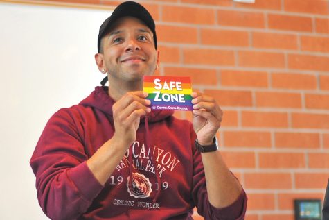 Alphabe+ Club President Enrique Duarte hold up a “Safe Zone” sign during his club’s “Out and About” even in Fireside Hall on May 9.