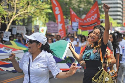 San Francisco residents Adela Martinez (left) and Maroorie Delgadillo (right) hold a multi-national flag as they chant during May Day march from Justin Herman Plaza to the Civic Center in San Francisco on Monday.