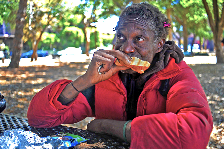 Ras, who wouldnt give his last name, eats a grilled cheese sandiwch provided by Munchie Movement volunteers at  Peoples Park in Berkeley on Friday. 