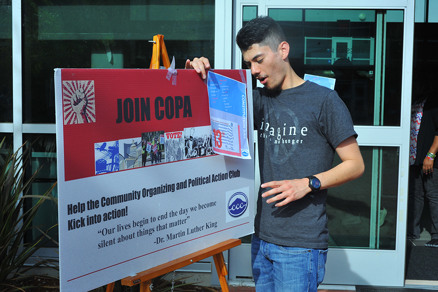 Club member Ricky Cusguen adjusts a Community Organizing and Political Action Club (COPA) sign outside Fireside Hall during a COPA event on Monday.