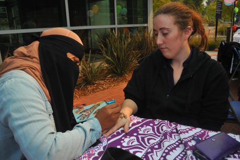 Nursing major Zahia Khan (left) applies henna dye on Irene Miles (right) during Club Rush festival in the Student Center Plaza on Oct. 13. 