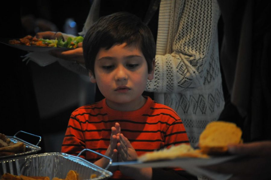 Richmond resident Qasim Abdulrahem rubs his hands as his
mother fixes him a plate during the Muslim Student Association Fast-A-Thon event at Fireside Hall on Thursday.