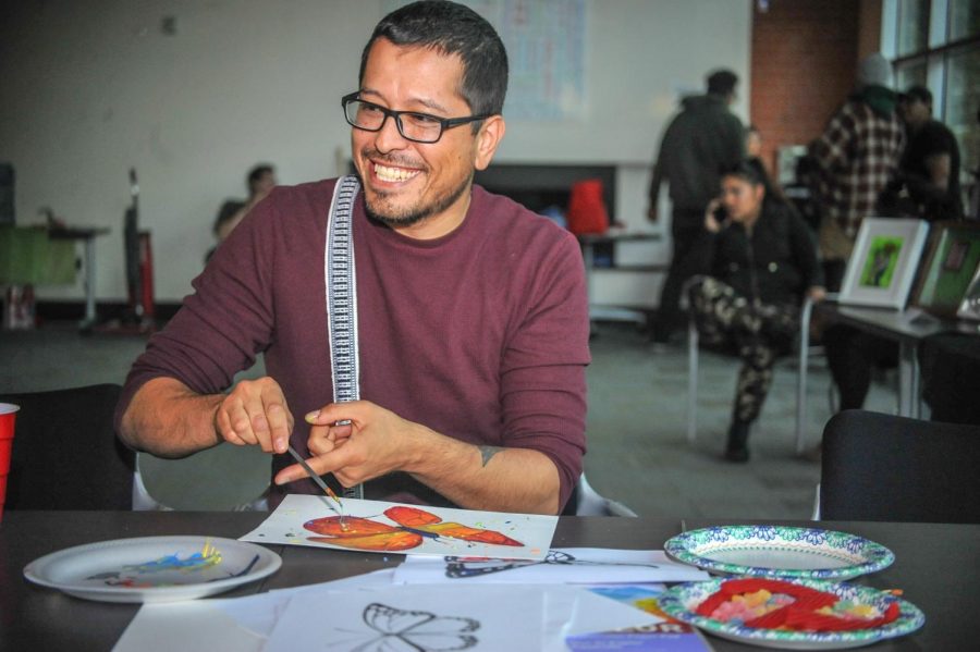 La Raza studies professor Augustine Palacios paints a butterfly during the “Exist to Resist” art show in Fireside Hall on May 2.