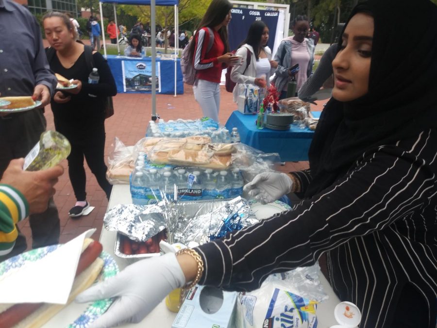 Liberal arts major Aber Mudhish hands out a hot dog  to eager students during Welcome Week on Aug. 28.