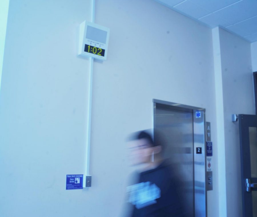 A student walks past one of the campuswide alert system boxes set up in the hallway of the second floor of the General Education Building.