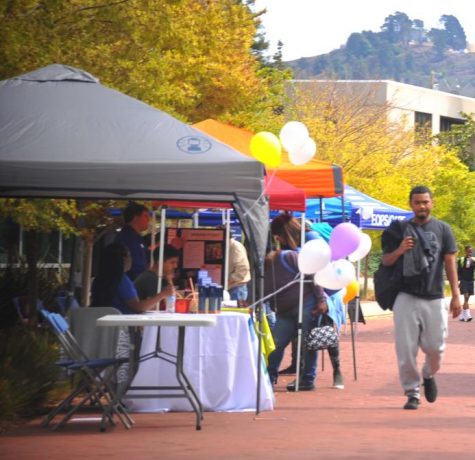 A student walks by booths set up during Comet Cash Day in the Campus Center Plaza on Oct. 3. 