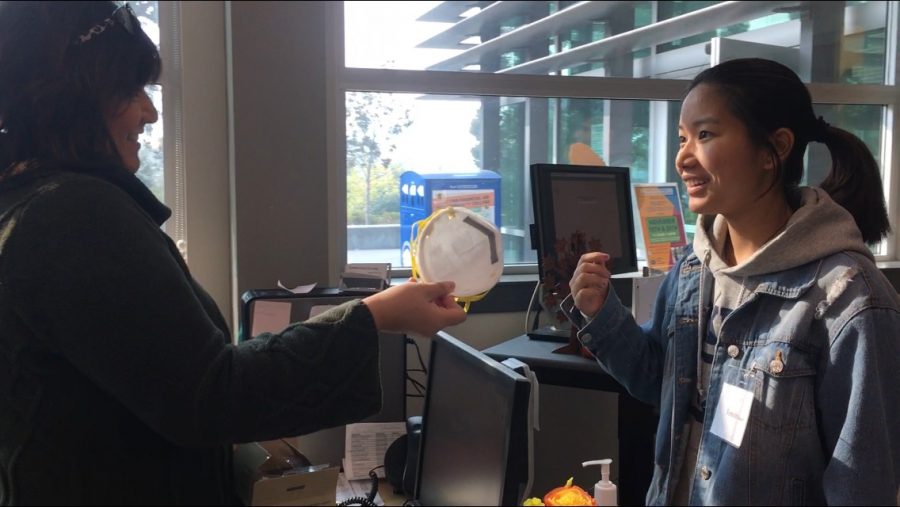 A student receives an N95 mask in the Welcome Center on Thursday.