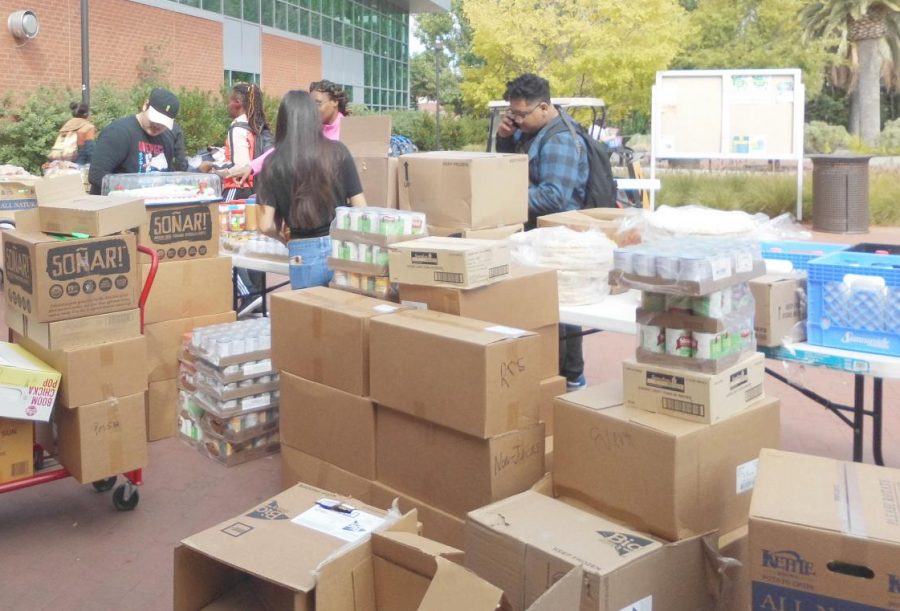 Students gather around a newly arrived shipment of food for the campus Food Pantry and begin unpacking it and take it to SA-234, where it is stored.