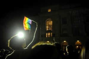 UC Berkeley student Jack Gil (left) holds up an LGBTQ+ flag in front of UC Berkeleys Wheeler Hall.