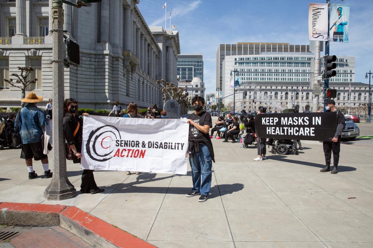 Demonstrators hold up signs designed by Senior and Disability Action outside San Francisco City Hall on April 16, 2024 in San Francisco, Calif.