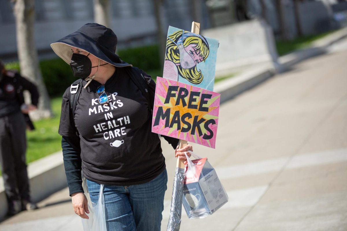 Britta Shoot carries a supply of free masks to give away at the Keep Masks in Health Care demonstration on April 16, 2024 in San Francisco, Calif.