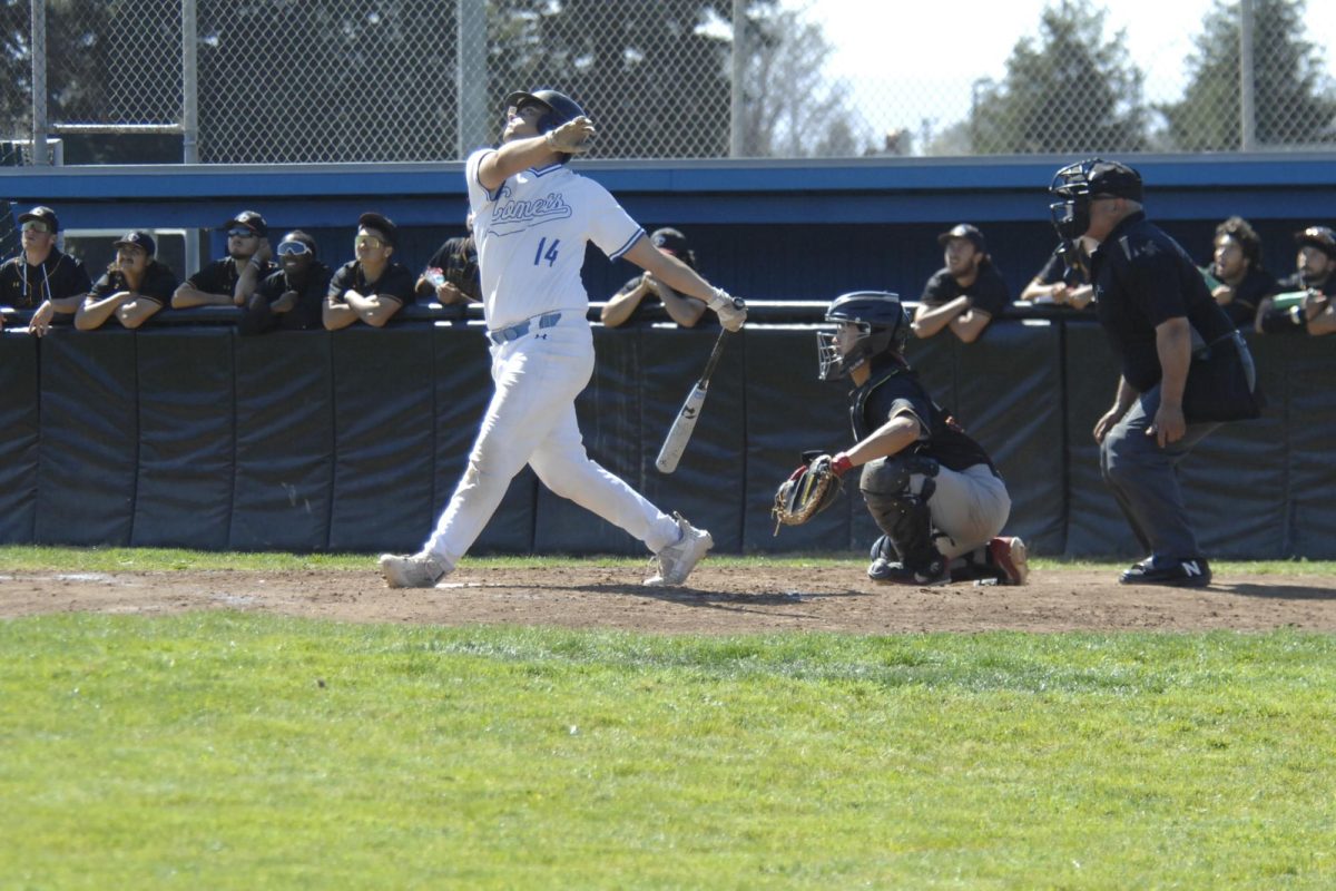 Contra Costa College player, Shane N. Bowen, drives the ball into the heavens as Los Medanos College players look on. Contra Costa College, Men’s Baseball game vs. Los Medanos College, San Pablo Ca 11 March 2024