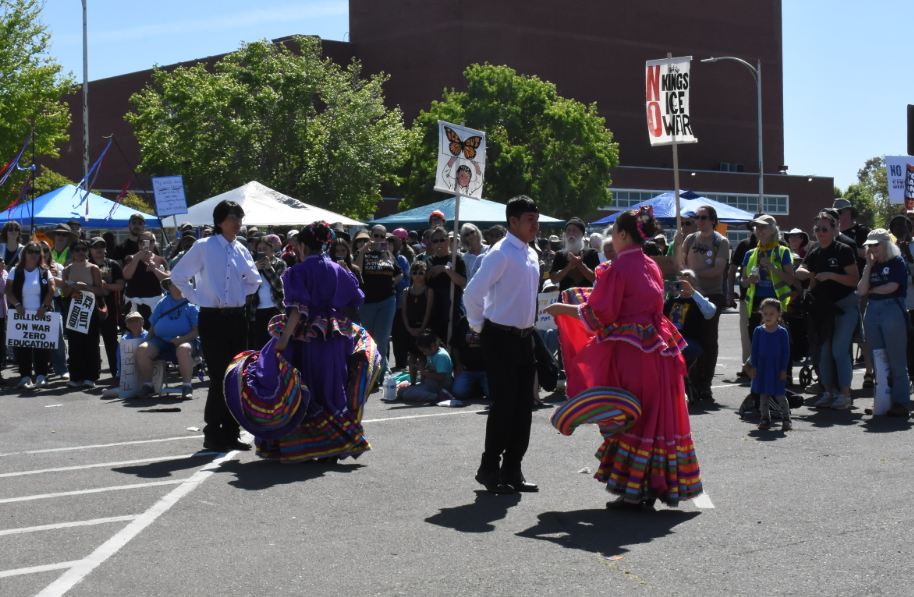 Richmond High School students perform traditional Mexican folklorico at the No Kings rally in Richmond, Calif. on March 28, 2026. Posters advocating for an end to the war in Iran and ICE hang in the background.